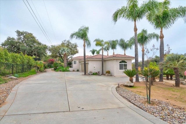 mediterranean / spanish home featuring driveway, a tile roof, fence, and stucco siding