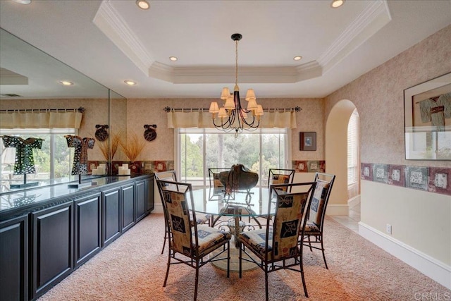 dining space with a tray ceiling, arched walkways, a notable chandelier, and ornamental molding