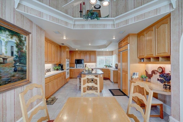 kitchen featuring light tile patterned floors, paneled fridge, recessed lighting, a center island, and a tray ceiling