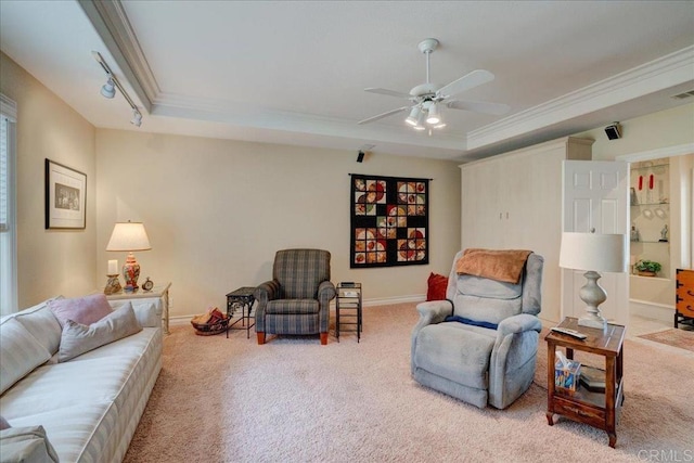 carpeted living area featuring ornamental molding, a raised ceiling, track lighting, and baseboards