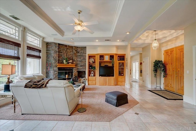 living area with ornamental molding, a wealth of natural light, a raised ceiling, and a fireplace