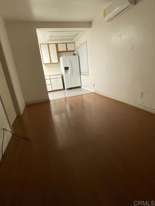 unfurnished living room featuring baseboards, an AC wall unit, and light wood-style floors