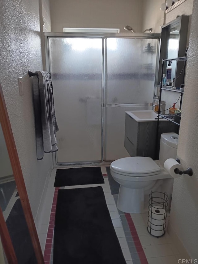 full bath with a stall shower, tile patterned flooring, vanity, and toilet