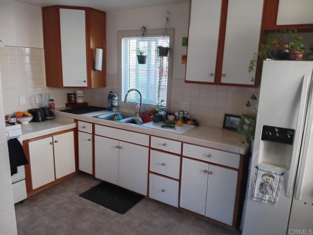 kitchen featuring white range, fridge with ice dispenser, white cabinetry, and a sink