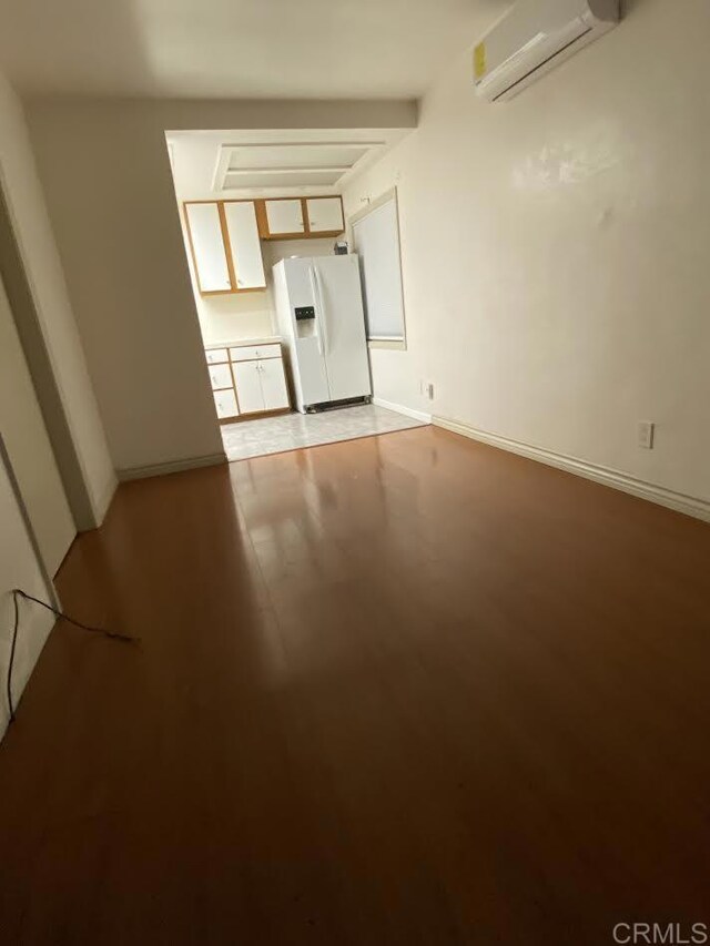 4169 Central Ave, San Diego, CA 92105 - unfurnished room with a wall unit AC, light wood-type flooring, and baseboards