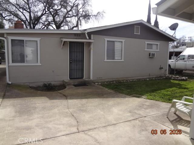 view of front of property with a patio, a wall mounted AC, and stucco siding