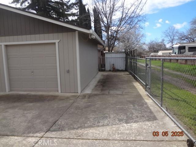 garage with driveway, a gate, and fence