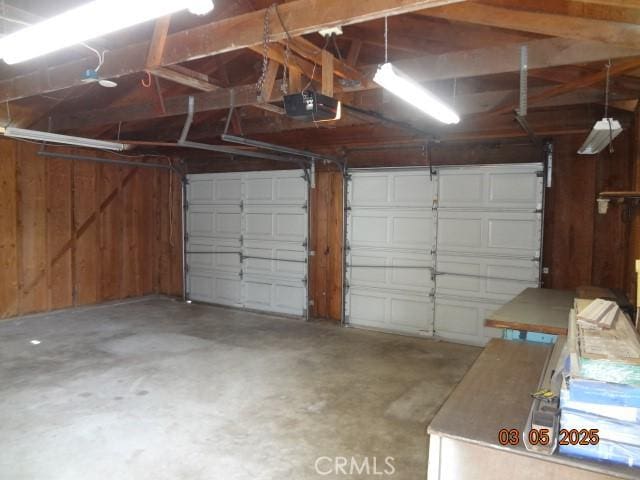 garage with wood walls and a garage door opener