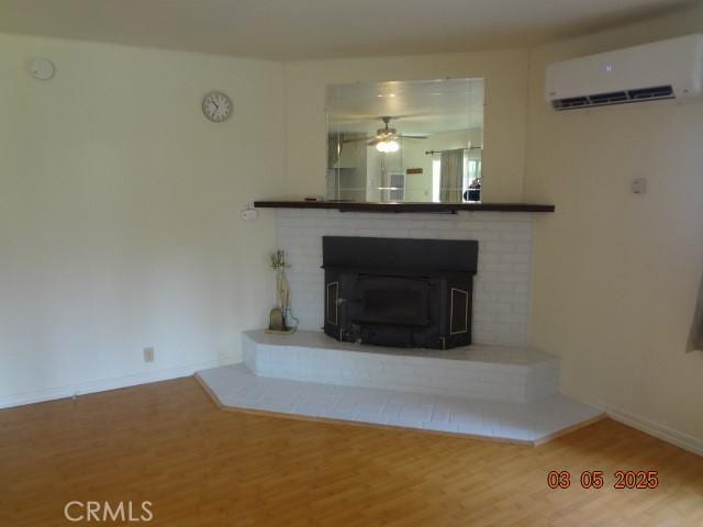 unfurnished living room with ceiling fan, a wall mounted AC, wood finished floors, and baseboards