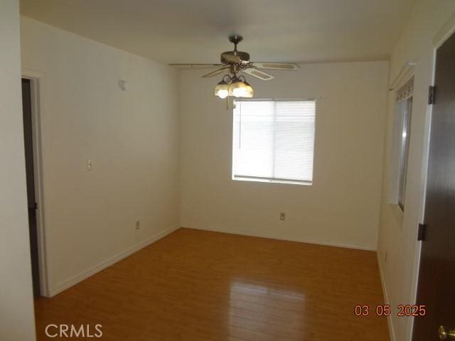 spare room featuring ceiling fan, baseboards, and wood finished floors