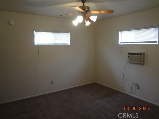 unfurnished room featuring baseboards, dark carpet, ceiling fan, and an AC wall unit