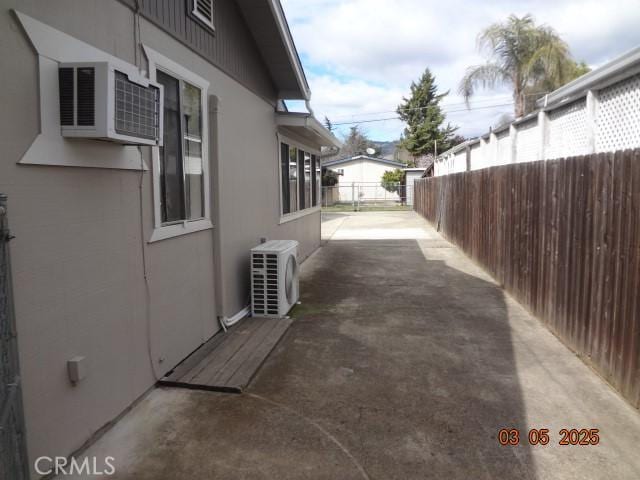 view of side of home with ac unit, fence, a patio, and stucco siding