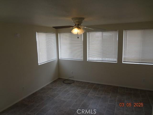 empty room with a ceiling fan and baseboards