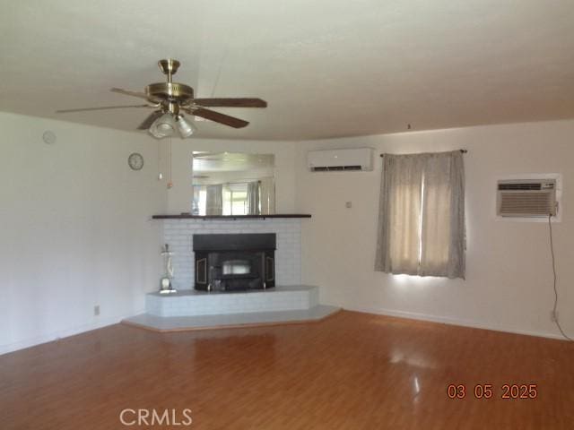 unfurnished living room featuring a wall mounted AC, a wall unit AC, wood finished floors, and a ceiling fan