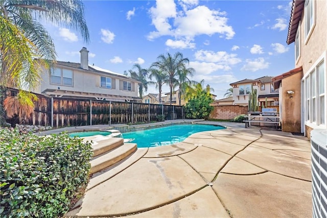 view of swimming pool with a patio, a fenced backyard, and a pool with connected hot tub