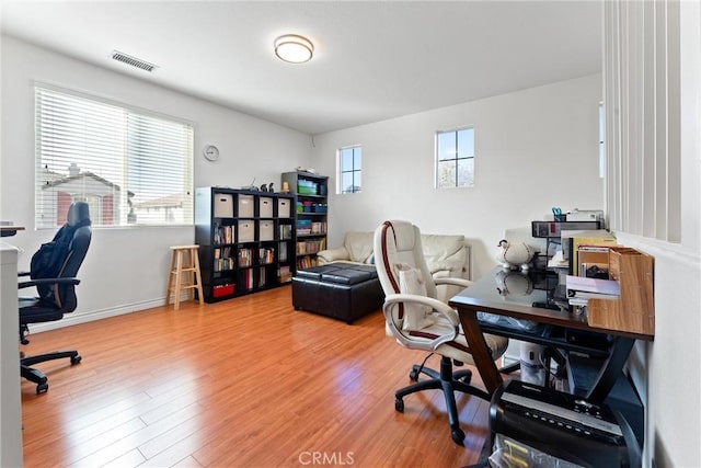 home office with wood finished floors, visible vents, and baseboards