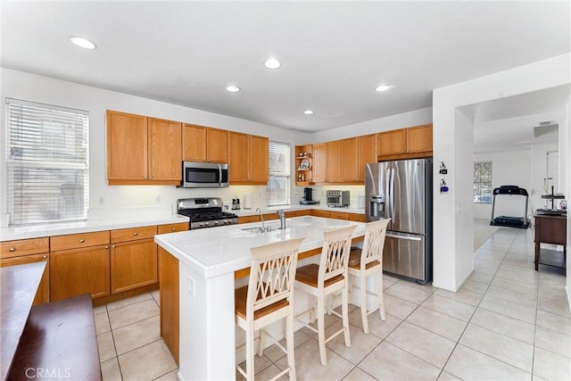 kitchen featuring a breakfast bar area, light tile patterned floors, a center island with sink, recessed lighting, and appliances with stainless steel finishes