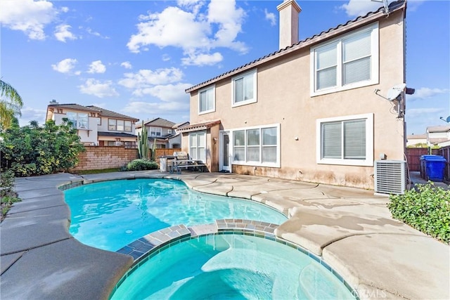 view of pool featuring central air condition unit, fence, a patio area, and a pool with connected hot tub