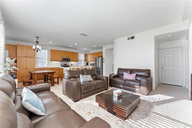 living room featuring recessed lighting, visible vents, a notable chandelier, and light colored carpet