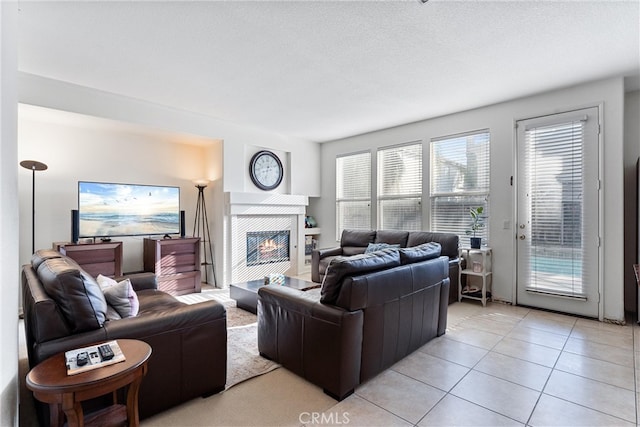 living area featuring a textured ceiling, light tile patterned flooring, and a fireplace