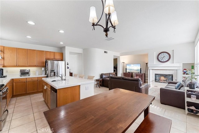 kitchen with open floor plan, stainless steel appliances, light countertops, and a kitchen island with sink