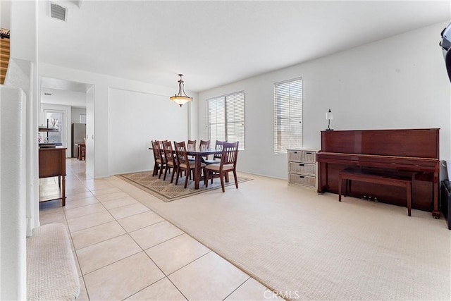 dining area with light tile patterned floors, visible vents, and light colored carpet