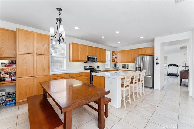 kitchen with recessed lighting, a kitchen island with sink, stainless steel appliances, hanging light fixtures, and light countertops