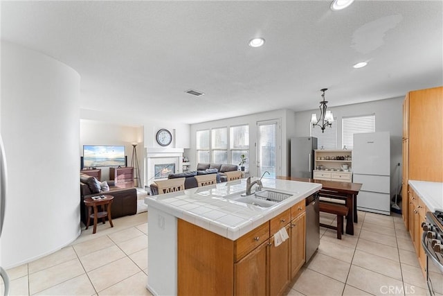 kitchen featuring a center island with sink, visible vents, a sink, stainless steel appliances, and open floor plan