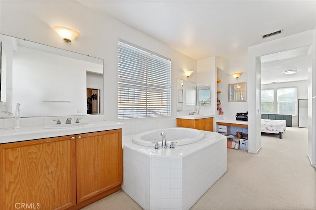 ensuite bathroom featuring visible vents, connected bathroom, a garden tub, and a sink