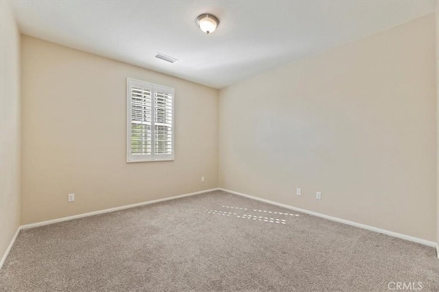 carpeted spare room featuring visible vents and baseboards