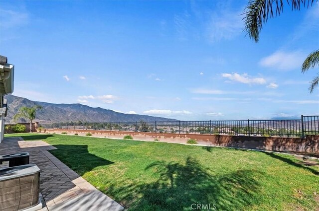 view of yard featuring central air condition unit, a patio area, fence, and a mountain view