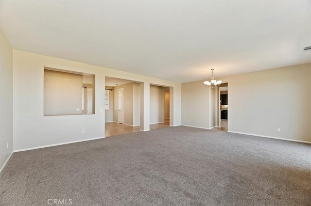 carpeted spare room with an inviting chandelier, visible vents, and baseboards