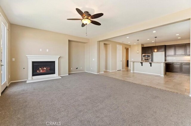 unfurnished living room featuring baseboards, a glass covered fireplace, light colored carpet, ceiling fan, and recessed lighting