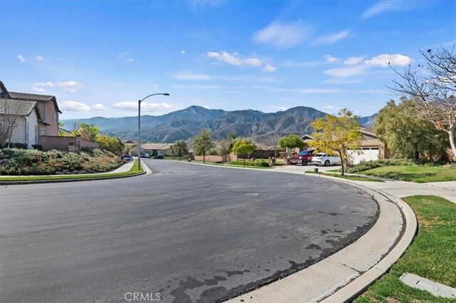 view of road featuring street lights, curbs, sidewalks, and a mountain view