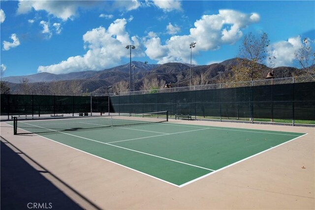 view of tennis court featuring fence and a mountain view