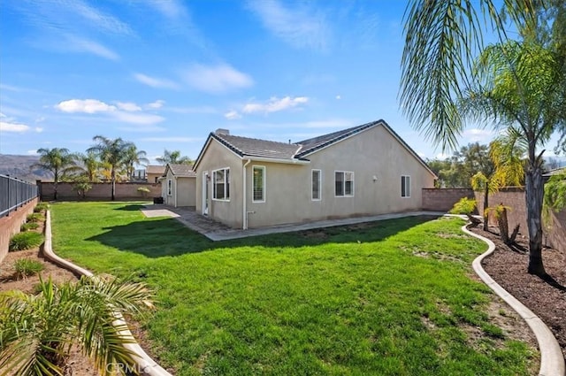 rear view of property with a patio area, a fenced backyard, a lawn, and stucco siding