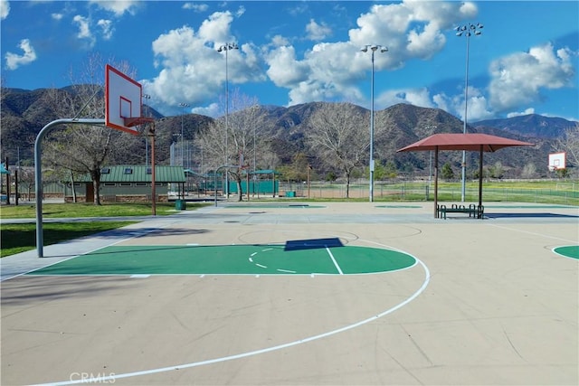 view of sport court featuring community basketball court, a mountain view, and fence