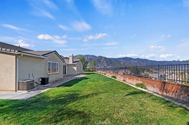 view of yard with fence, a mountain view, and central AC