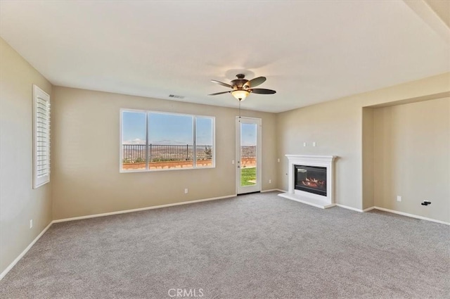 unfurnished living room featuring carpet, a glass covered fireplace, and baseboards