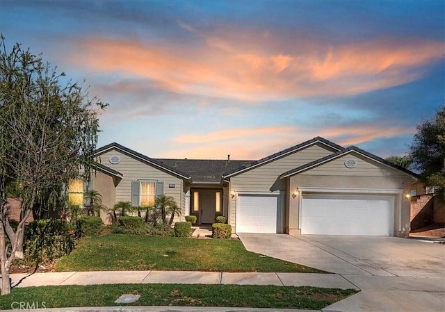 ranch-style house featuring a garage, a front lawn, and concrete driveway