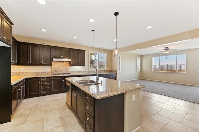 kitchen with dark brown cabinetry, recessed lighting, under cabinet range hood, a sink, and light stone countertops