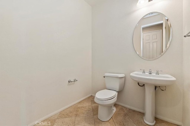 bathroom featuring toilet, baseboards, a sink, and tile patterned floors