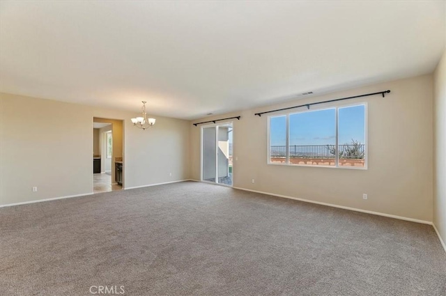 spare room with carpet floors, a notable chandelier, baseboards, and a barn door