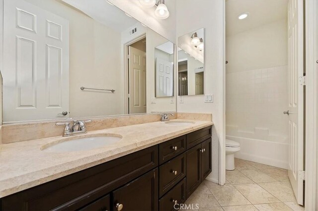 bathroom featuring tile patterned flooring, a sink, toilet, and double vanity