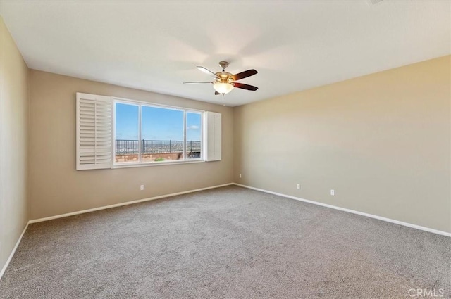 carpeted empty room with ceiling fan and baseboards