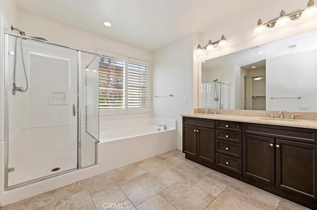 full bath with double vanity, a stall shower, a garden tub, and a sink