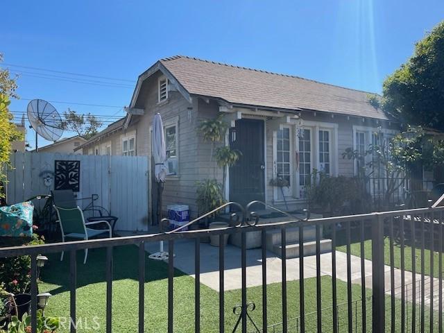 bungalow-style house with a shingled roof and a fenced front yard