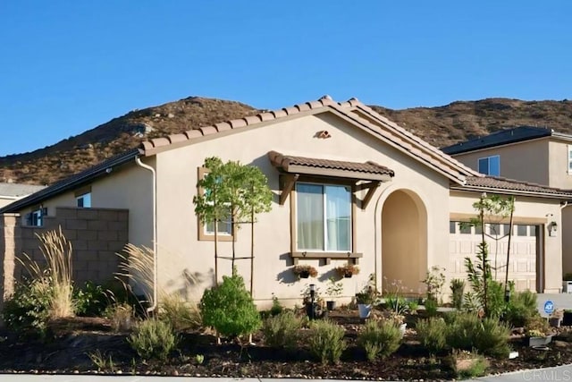 exterior space featuring a mountain view, a tiled roof, an attached garage, and stucco siding