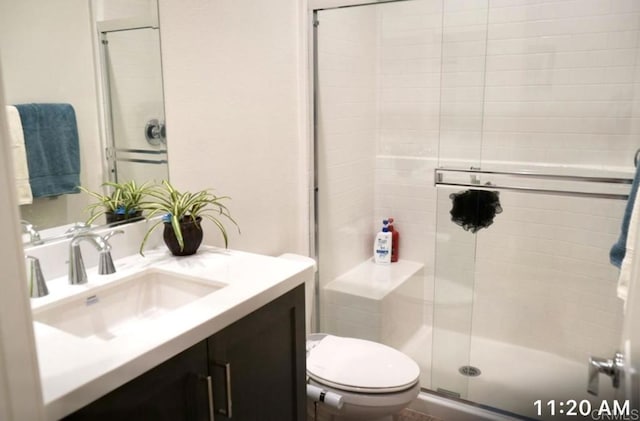 bathroom featuring toilet, a stall shower, and vanity