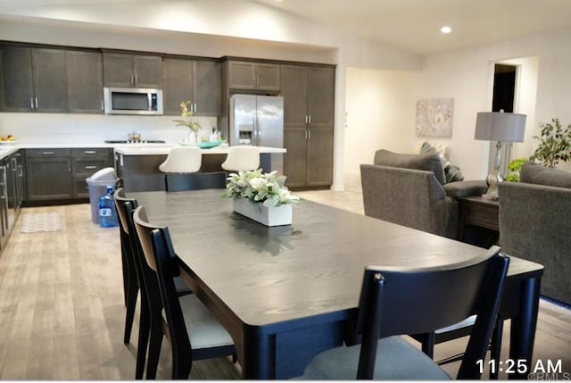 dining area featuring light wood finished floors, vaulted ceiling, and recessed lighting